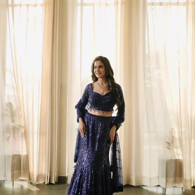 A full-length shot of a glamorous navy blue sequin lehenga. The indoor lighting and elegant backdrop make it perfect for a reception or cocktail party lookbook.