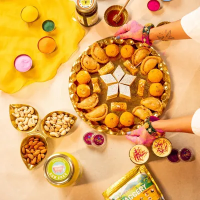 A vibrant flatlay of Holi essentials, from colorful powders to traditional sweets and nuts. This top-down shot captures the festive preparation and abundance, perfect for a brand's Holi campaign visuals.