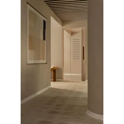 This corridor in the 'Crème' wellness center showcases our concept of creating a seamless, flowing space. The walls, floor, and even the curved column are finished in the same soft, creamy texture, creating a monolithic effect that is both calming and sophisticated.