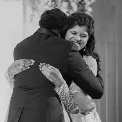 A powerful and emotional black and white photo of a bride sharing a tight hug, capturing a moment of overwhelming love and joy.