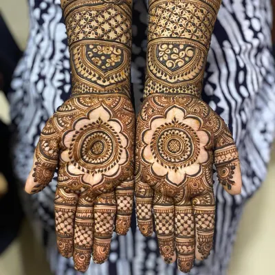 A full-coverage design featuring a large floral mandala on the palm and intricate jaali (net) patterns on the wrist cuffs. This is a classic bridal look that feels both traditional and timeless.
