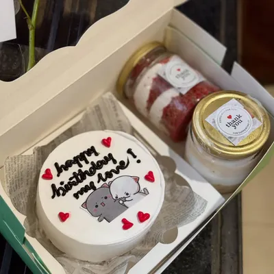 An adorable birthday hamper featuring a bento cake with a cute "Mochi Mochi Peach Cat" design. It's paired with two delicious cake jars, one red velvet and one vanilla.
