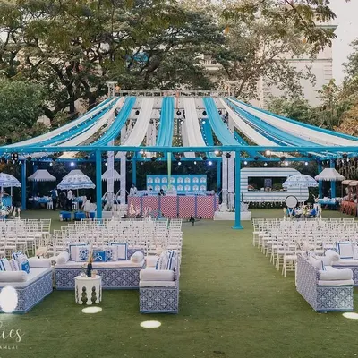 A wide view of the 'Bar Palladio' inspired Haldi for Yasha and Rahil. The venue was transformed with a canopy of blue and white drapes, custom-printed lounge seating, and a fresh, non-traditional color palette.