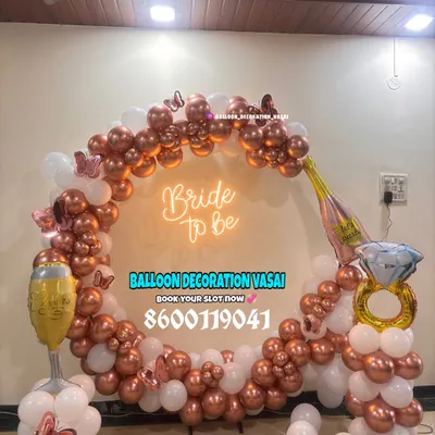 Celebrate the bride-to-be with a fun and trendy setup. This rose gold and white balloon ring arch, complete with a neon sign and playful props, is perfect for party photos.