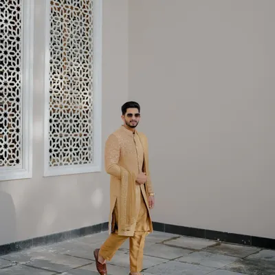 A stylish groom in a golden sherwani. This is a perfect look for a grand wedding or reception, captured beautifully here.