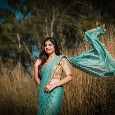 This dynamic shot from a photoshoot captures a soft, ethereal look. The makeup is natural and glowing, and the flowing saree adds a sense of movement and artistry.