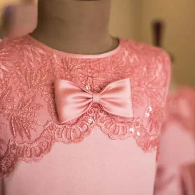 A close-up of the exquisite craftsmanship I put into every dress. This image showcases a delicate pink lace overlay, adorned with tiny sequins and a perfectly tied satin bow for a touch of elegance.