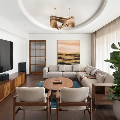 This view of the West Coast Residence shows how we balance different elements. The large sectional sofa provides comfort, while the sculptural coffee table and statement wooden ceiling light add layers of artistic expression to the living area.