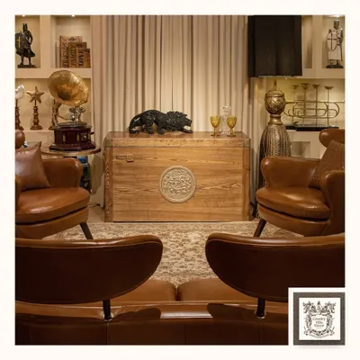 The Treasure Chest automated bar, pictured here in its closed state. It functions as a beautiful vintage-style trunk, crafted from solid ash wood with a distinctive front medallion, adding character to any room.