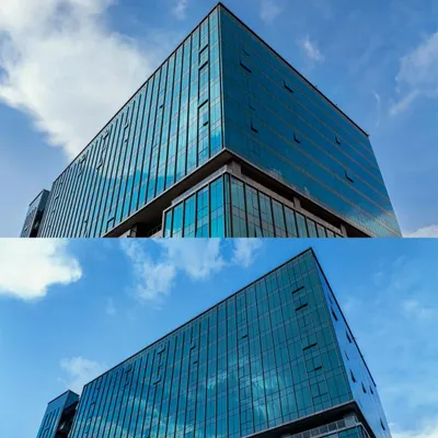A low-angle aerial shot of the glass facade of a building at ITPL Tech Park, emphasizing its modern design against a clear blue sky. This is ideal for corporate branding and architectural portfolios.