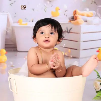 A classic splash session moment, with a baby looking up curiously from a mini bathtub. The bubbles and rubber ducks floating around add to the playful and fun atmosphere of the shoot.