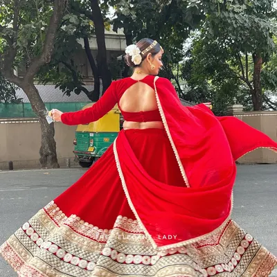 A full view of the stunning backless design and the beautiful flare of my red velvet bridal lehenga. The wide, embroidered border adds weight and grandeur, making it perfect for those classic twirling shots.