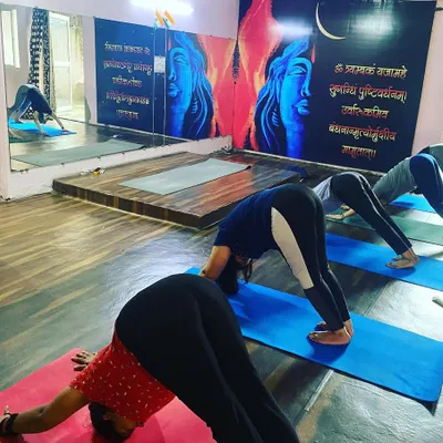 A typical teacher training session at our Noida studio. Here, students are in Adho Mukha Svanasana (Downward-Facing Dog), a foundational pose we break down in detail to understand its alignment and benefits. The large mirror helps students self-correct their posture.
