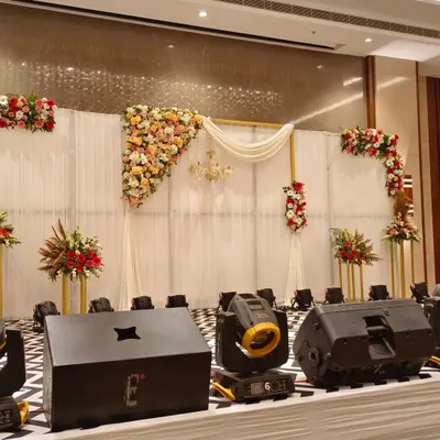 I designed this premium stage for a corporate function, combining elegant white fabric draping with asymmetrical floral arrangements. The setup included professional uplighting to create a sophisticated focal point for the event.
