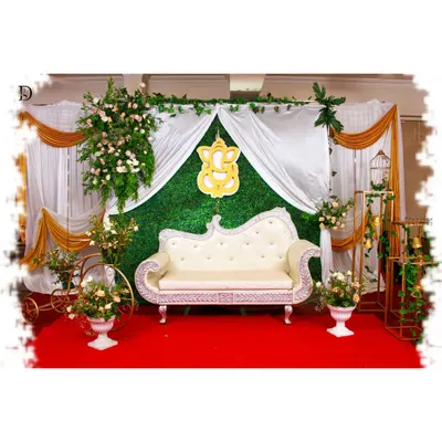 This elegant baby shower setup features a lush green grass wall as the backdrop. I used white and gold drapes, a Ganesha cutout, and floral arrangements on props like a decorative tricycle to complete the look.