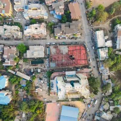 A wider aerial perspective of the construction site, showing its location within the surrounding neighborhood. This contextual drone shot is valuable for real estate marketing and urban planning documentation.