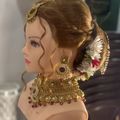 A traditional bridal bun or 'khopa' created on a mannequin head. This style is adorned with flowers and jewelry, and mastering it is essential for any bridal artist.