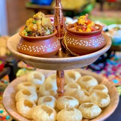 A creative chaat station perfect for a festive party. I serve golgappas on a two-tiered wooden stand, with the fillings presented in traditional terracotta matkas for an authentic yet stylish touch.