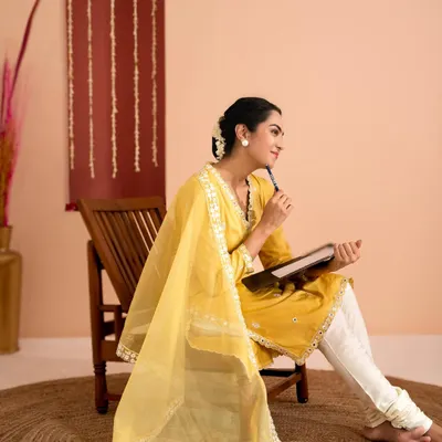 This studio portrait for an ethnic wear brand captures a thoughtful, elegant mood. The warm tones of the background complement the yellow kurta, while the pose highlights the flow of the dupatta.