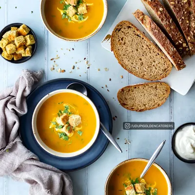 A comforting bowl of our creamy pumpkin soup, garnished with croutons and fresh herbs, and served with slices of multigrain bread. A wholesome start to any meal.