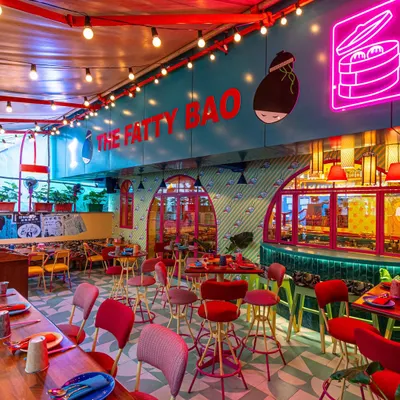 A wide shot of The Fatty Bao's interior, capturing the playful chaos of neon signs, colorful furniture, and graphic wall art. This type of image is perfect for showing customers the fun and lively atmosphere they can expect.