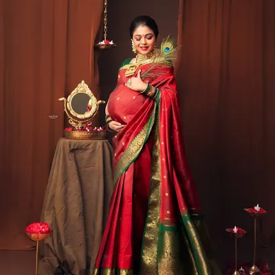 This mamma looks like royalty in her beautiful red and green silk saree. We styled the studio with traditional props like a brass mirror and diyas to complete the look.