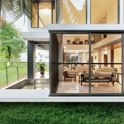 This design, named "Synthesis," perfectly illustrates our philosophy of blurring boundaries. The living room's floor-to-ceiling glass walls slide open to connect directly with the lawn and an outdoor water feature.
