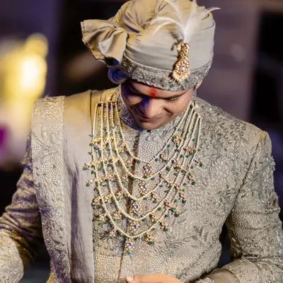 A close-up of the groom's wedding day look. We customized this Ankit V Kapoor sherwani to a sage green and paired it with a magnificent multi-layered pearl and emerald necklace to complete his royal ensemble.