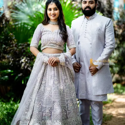 A full-length view of our coordinated lavender lehenga and sherwani set. The intricate silver embroidery is consistent across both outfits, creating a truly unified and elegant appearance for your couple photoshoot.