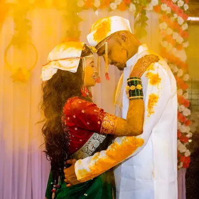 A beautiful, intimate moment during a Haldi ceremony. The golden glow of the turmeric and the couple's embrace create a warm and emotional photograph.