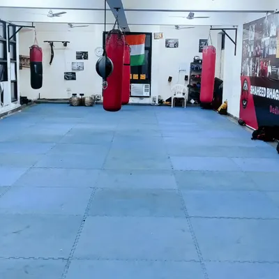 A full view of our training floor, equipped with multiple heavy bags and open mat space for drills and conditioning. This is our ground for hard work.