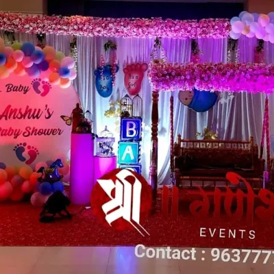 A modern baby shower decoration with a personalized backdrop for Dr. Baby Anshu. The setup includes a colorful balloon arch, a decorated swing, and light-up 'BABY' blocks.