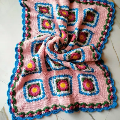 This is the Lydia blanket, a beautiful floral design made of many individual squares joined together. The swirling fabric shows the soft drape and generous size of the finished throw.