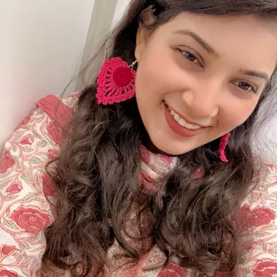 A clear, happy selfie showing the true size and vibrant color of my pink heart-shaped earrings. They are large enough to make a statement but light enough to forget you are wearing them.