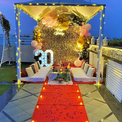 A breathtaking 30th birthday party on a terrace, featuring a lit cabana, a red carpet, and a sequin backdrop for a truly glamorous celebration.