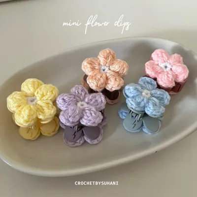A close-up of my mini flower clips, displayed in a dish to show the variety of pastel colors available. Each clip features a small, detailed crochet flower on a secure clip base.
