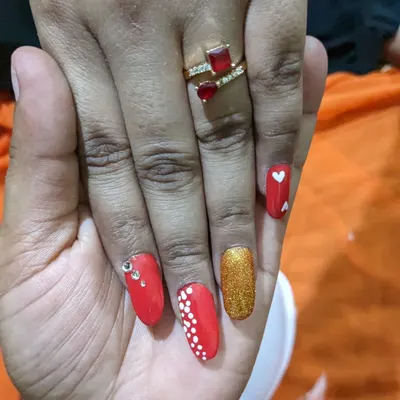 A bold and festive set of permanent nail extensions. This design combines classic red, sparkling gold glitter, delicate dot work, and even a few rhinestones for extra shine.