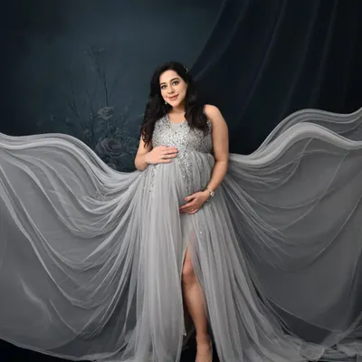 A vision in silver. This portrait uses a flowing grey gown and a dramatic fabric toss to create a sense of movement and ethereal beauty against a dark, moody backdrop.