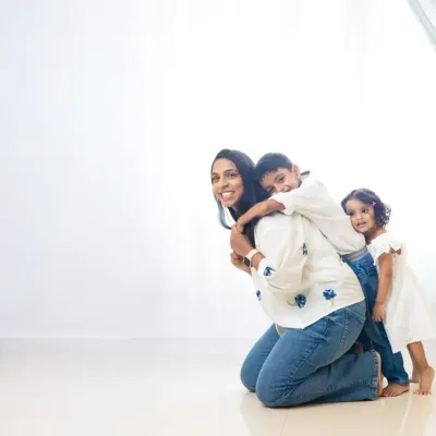 A mother and her children share a playful, loving moment against a clean, white background. This minimalist style allows their genuine emotions to be the focus of the photograph.