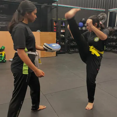 A fantastic high kick demonstrates the power and flexibility we build in our classes. This student is practicing her technique on the pads, focusing on height and form.