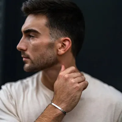 A man in a simple t-shirt wearing a silver cuff bracelet. The bracelet adds a touch of refined style to a classic, casual look.