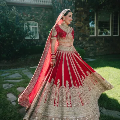 A stunning full-length portrait of the bride, Nita, in her traditional red and gold lehenga. The twirl of the skirt shows off the magnificent craftsmanship of her attire.