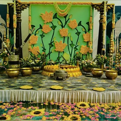 A spectacular Haldi stage setup featuring a custom backdrop of marigold flowers and traditional motifs. The poolside setting is decorated with floating flowers, creating a truly immersive experience.