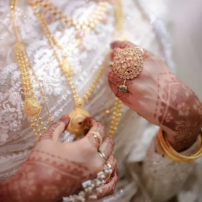 A close-up on the bride's hands, adorned with intricate henna and stunning gold jewelry. These details are a beautiful part of the bridal story.