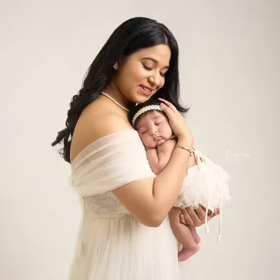 A mother's gentle embrace, holding her newborn daughter close. This portrait captures the overwhelming love and tenderness of the first few days of motherhood in a simple, elegant studio setting.