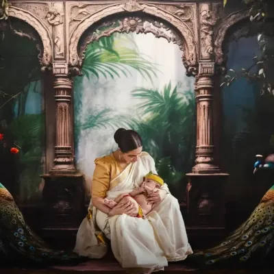 This is another angle from the iconic Janmashtami shoot, showing the mother looking down at her child. This artistic portrait session involved a custom backdrop and careful styling to create a painterly, divine image celebrating motherhood.