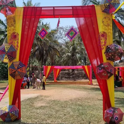 Another view of the festive entrance for the GIVA Holi corporate event, showcasing the vibrant yellow and red drapes and decorative umbrellas.