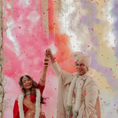 A moment of pure celebration for the newly married couple. The groom is radiant in our classic ivory sherwani, featuring subtle all-over embroidery that perfectly complements the festive atmosphere.