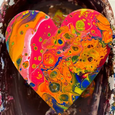 A close-up of a finished fluid art heart, bursting with vibrant orange, pink, and blue cells. Using silicone oil helps create these incredible, organic patterns, and we'll show you how.
