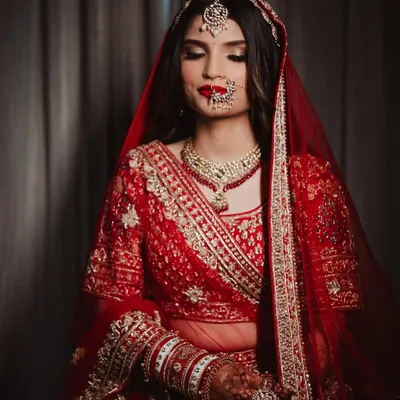 A moment of serene beauty before she says 'I do'. This classic red bridal look, complete with a bold lip and traditional jewelry, is the epitome of timeless elegance.